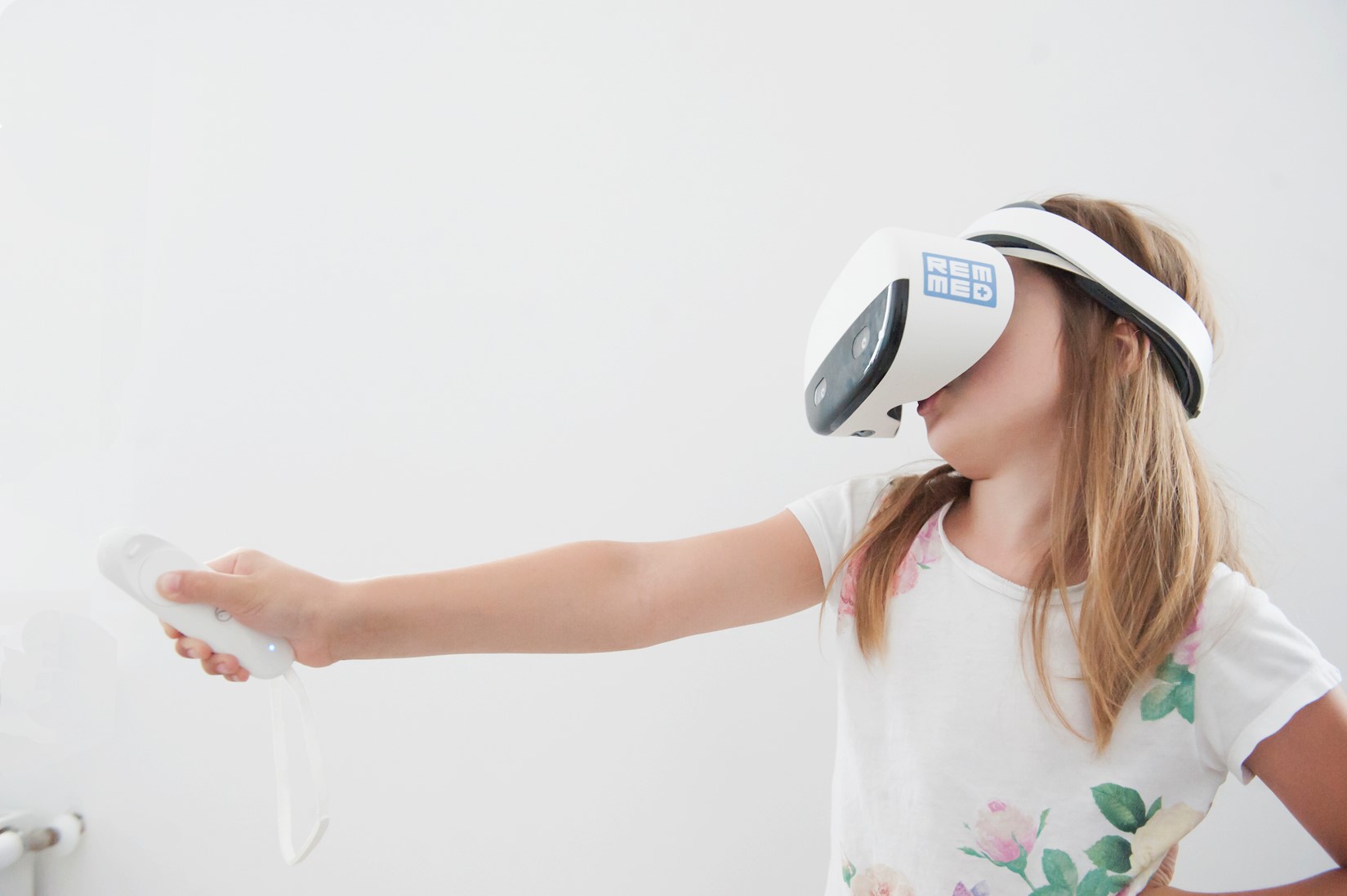 dziewczynka z założonymi na głowę goglami VR w białym kolorze z napisem 